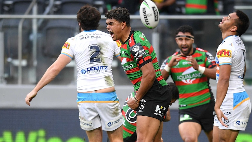Latrell Mitchell screams as the ball bounces up in the air behind him after scoring a try for the Rabbitohs against the Titans.
