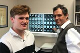 Professor points to brain scans while standing in his office.