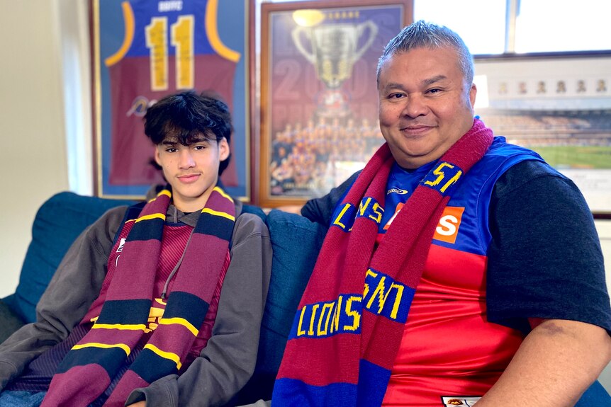 Archie and Gilbert Liu wear Brisbane Lions merchandise while sitting in front of framed memorabilia