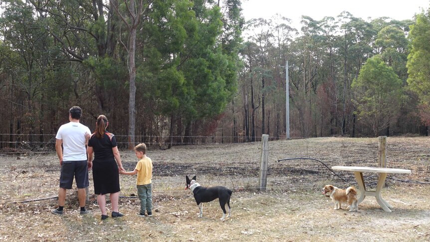 The burnt out fire area, close to the family home with three people looking on