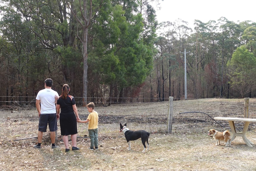 The burnt out fire area, close to the family home with three people looking on