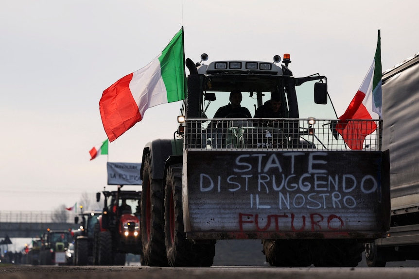 A tractor drives on the highway with Italian flags.