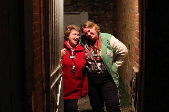 Rose Robinson and Debbie Piller stand inside a gaol cell together. 