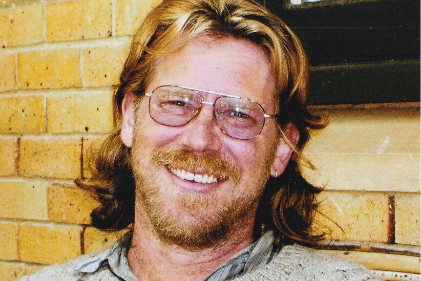 A man in glasses smiles at the camera.