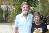 Joan and David Fensom stand within a bunch of palm trees