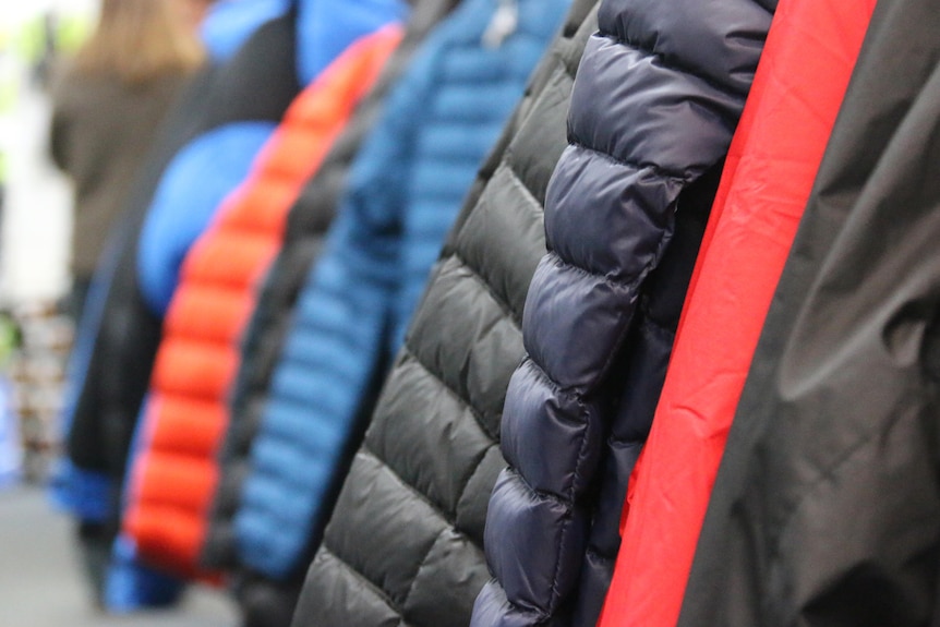Puffer jackets on display hanging on a rack.