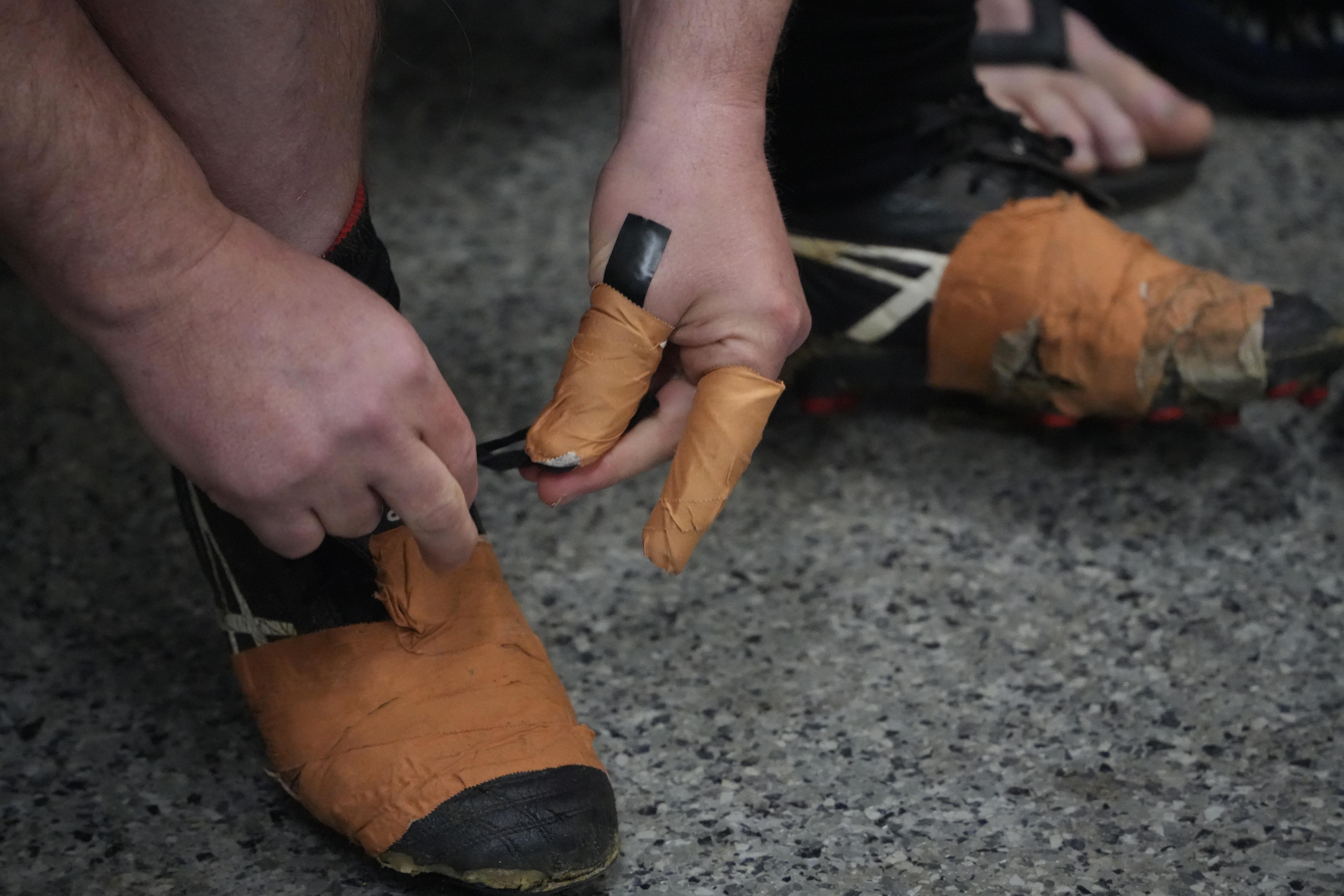 Heavily taped up fingers tying the laces of heavily taped up football boots