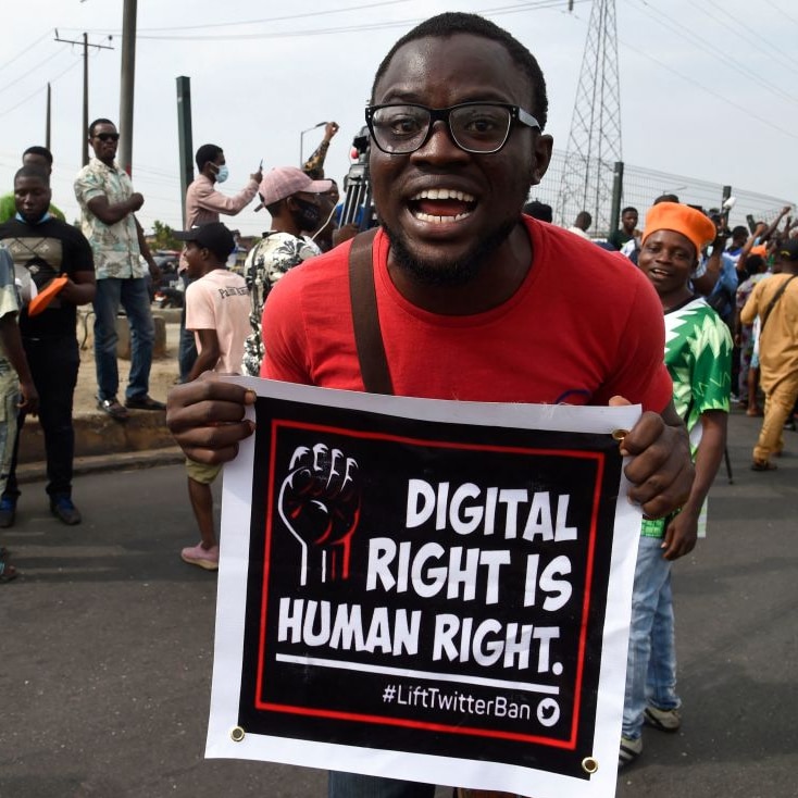 A man yells as he holds up a banner at a street protest opposing the Nigerian government's ban on Twitter use