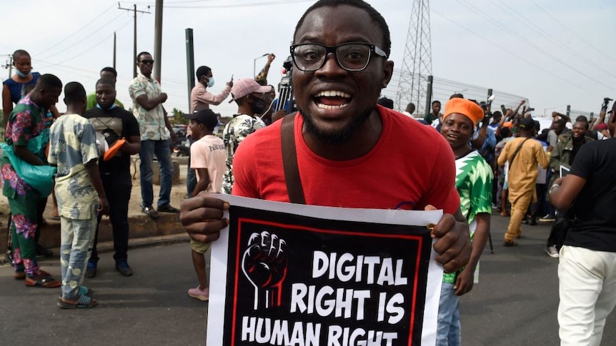 A man yells as he holds up a banner at a street protest opposing the Nigerian government's ban on Twitter use