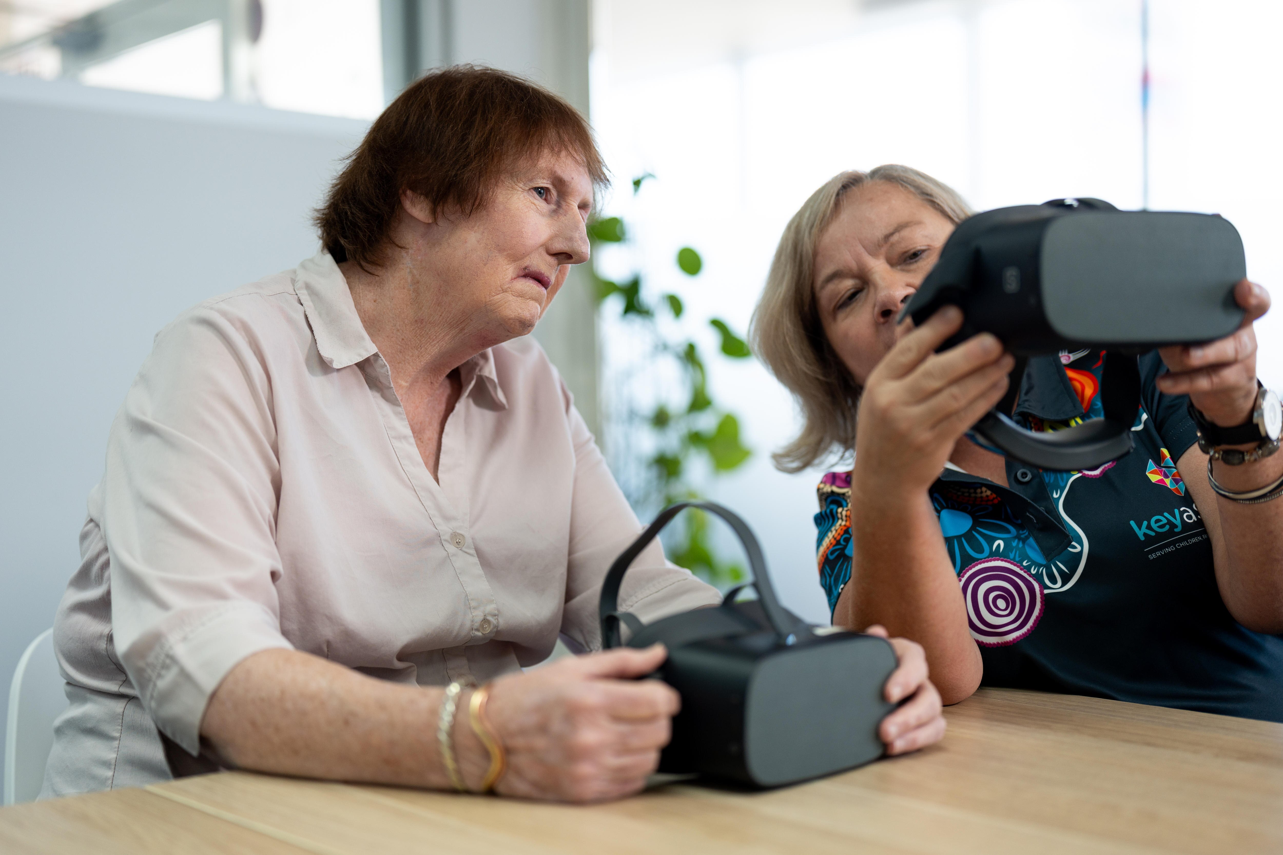 Key Assets social worker Lana Valenta holds a VR head set which she shows to foster carer Louise