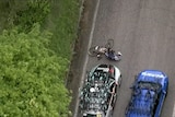 A man lies on the ground in front of a car with his bike next to him as seen from above.