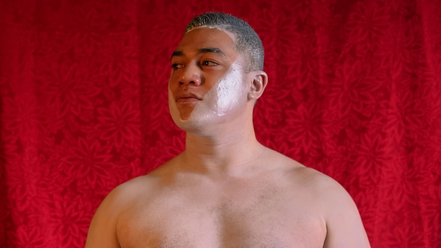 A man wearing traditional Tongan dress stands proudly.