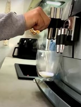 A hand turns on a coffee machine.