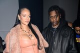 Rihanna and ASAP Rocky standing and posing for photos at a fashion show.