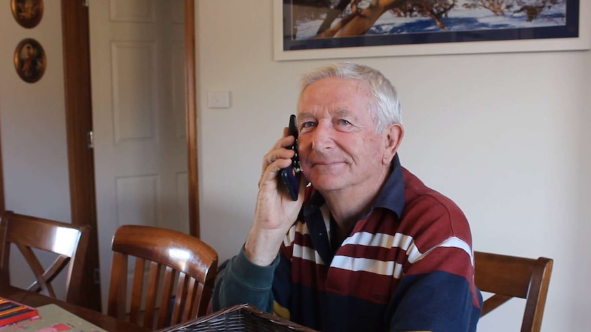 Korrie Kueper holds a phone up to his ear, while looking into the camera.