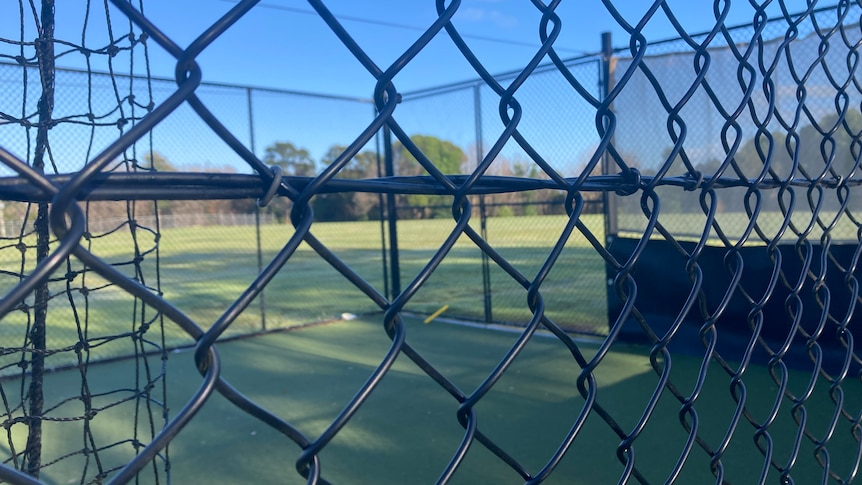 Close up photo of wire netting with sport field in the distance.