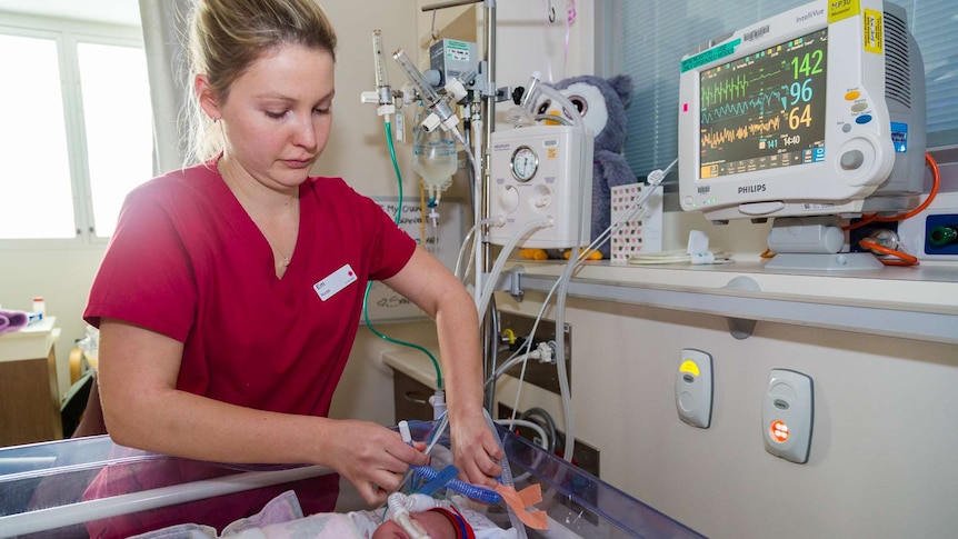 A nurse fixes the breathing tube of a baby