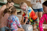 A young boy performs CPR on a dummy as other children look on.