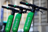 Lime scooters lined up along the footpath.