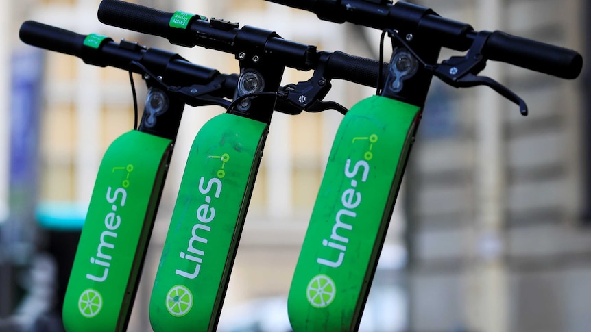 Lime scooters lined up along the footpath.