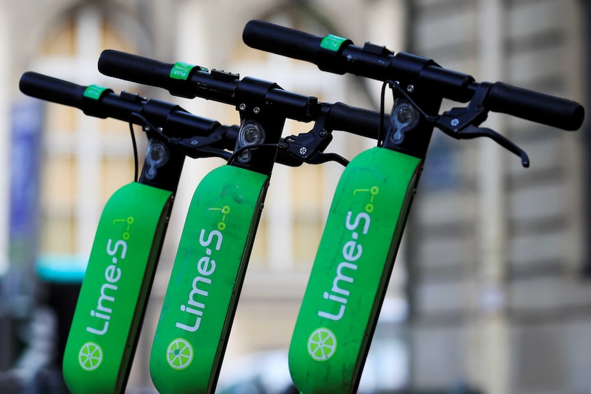 Lime scooters lined up along the footpath.