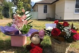 Two bunches of flowers and a stuffed toy monkey in front yard of home