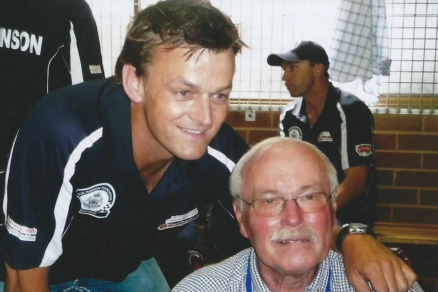 A young sportsman and an older, balding man with a moustache in a dressing room.