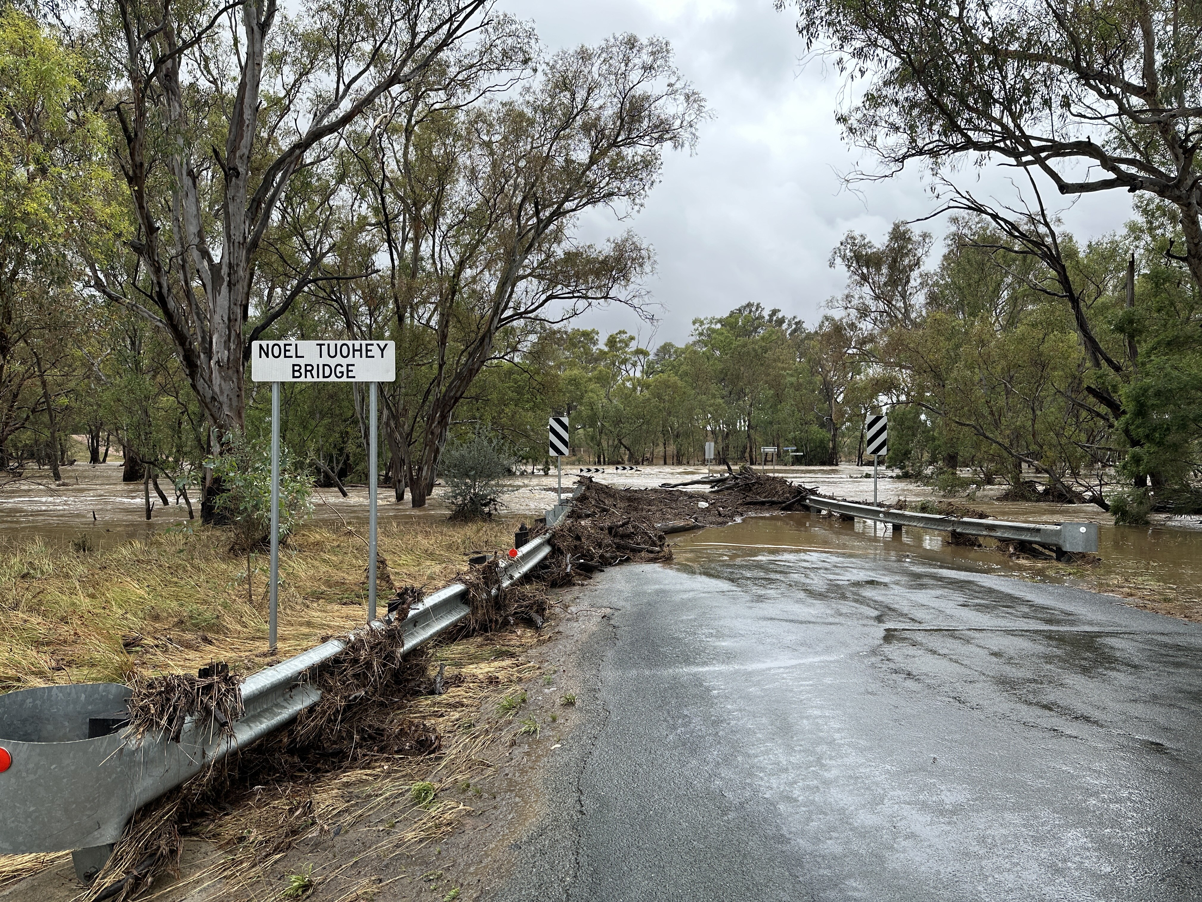 A road with floodwater covering it and debris all over road