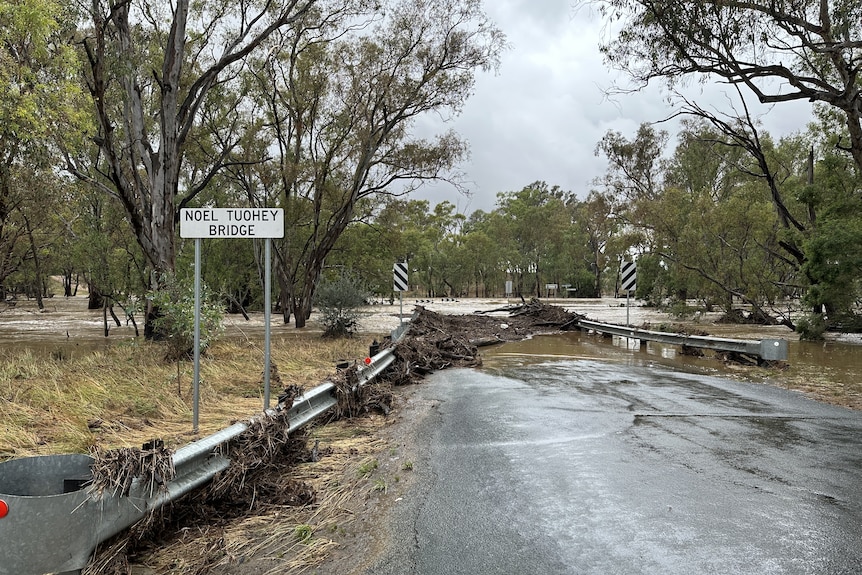 A road with floodwater covering it and debris all over road
