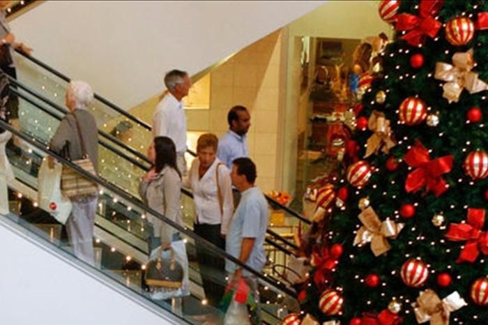 Shoppers in a department store surrounded by giant Christmas trees