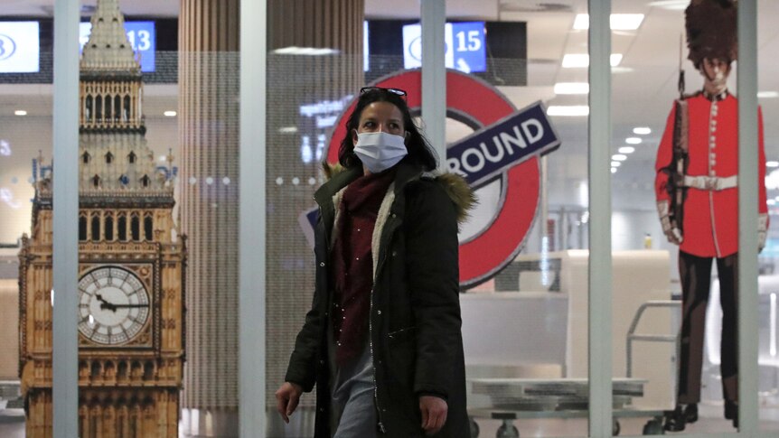 A woman in a mask walks past the closed entrance of the Eurostar terminal at Brussels South railway station