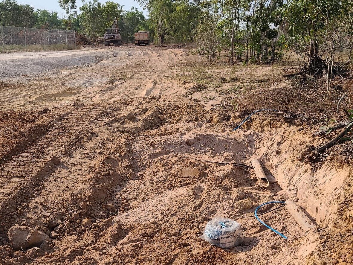 rural work site showing a snapped cable with a digger and a truck in the background.