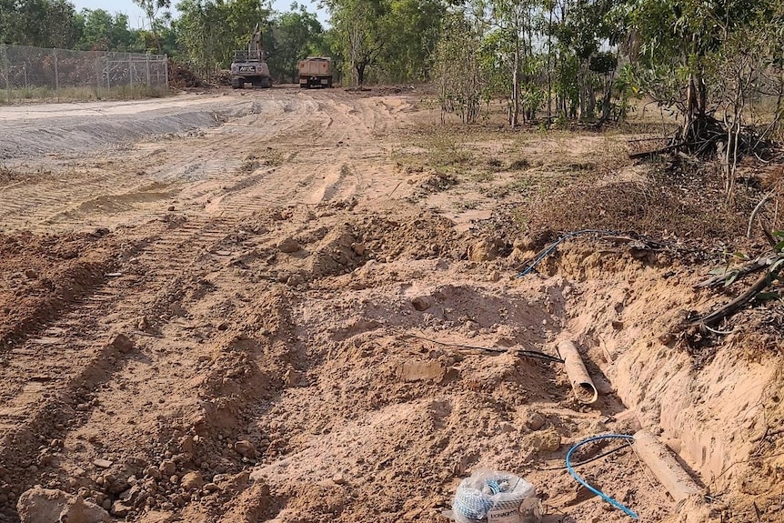 rural work site showing a snapped cable with a digger and a truck in the background.