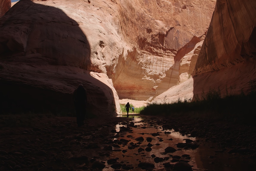 A woman walks through a canyon.