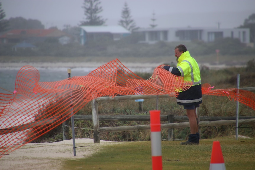 A worker secures a warning fence around collapsed dunes at a Lancelin beach.