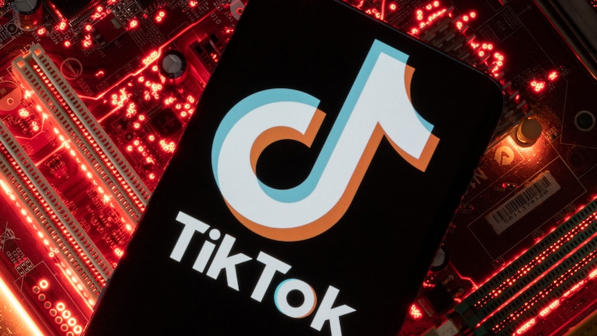 A smartphone with the TikTok logo displayed on its screen sits on a glowing red computer motherboard.