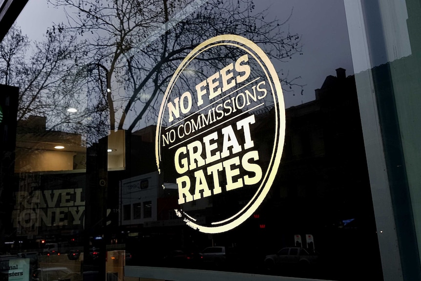 A sign on a Travel Money Oz storefront that reads "No Fees, No Commissions, Great Rates."
