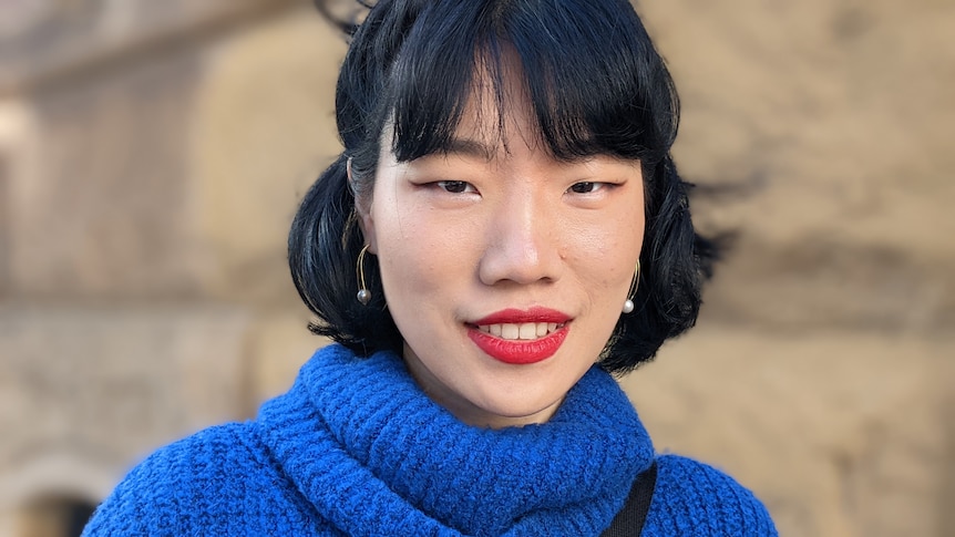 A Chinese woman with short black hair, red lipstick and blue jumper.