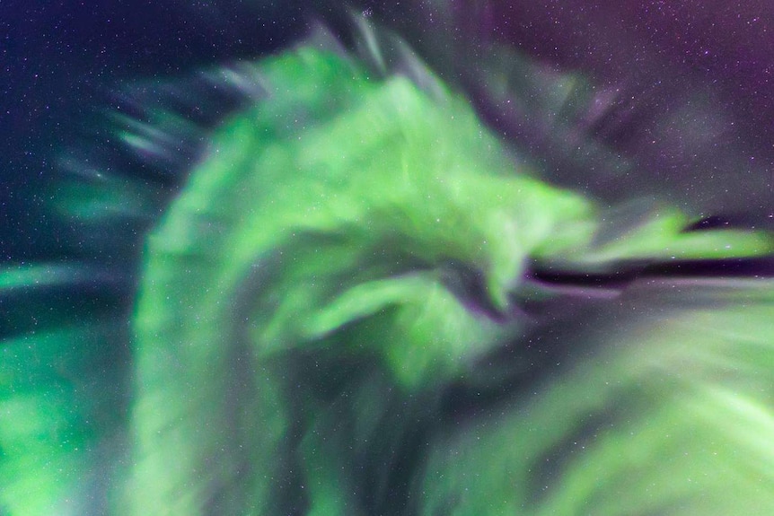 The shape of a dragon's head can be seen in the green and purple lights streaking the night sky.