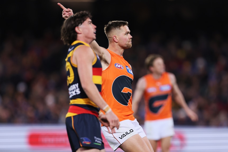 A GWS AFL player points a finger into the sky as he celebrates a goal against Adelaide.