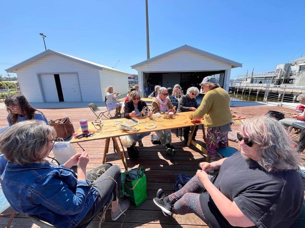 women chatting and weaving around tables on slipway deck 