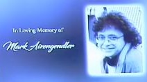 A slide at a funeral for a man with long curly hair and glasses