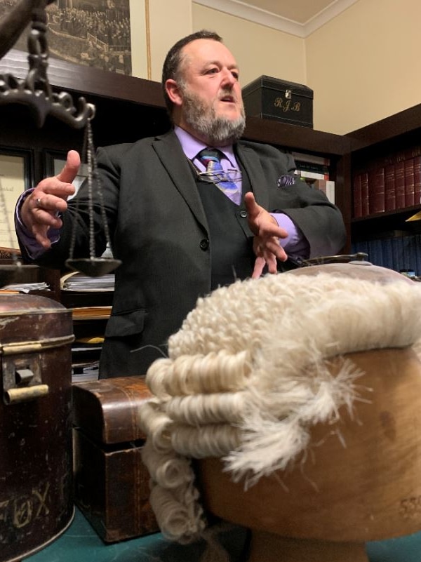 Ray Broomhall standing with his wig collection.