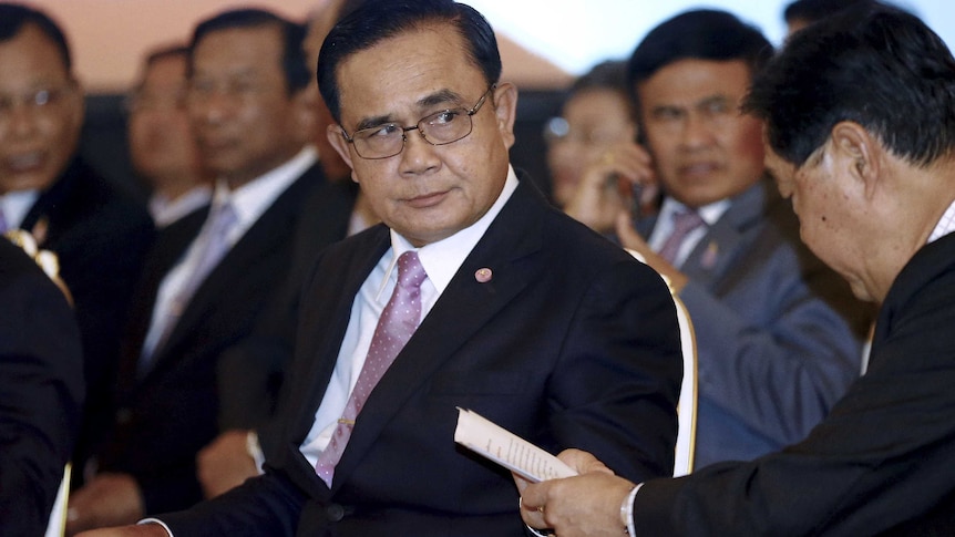 Prime Minister Prayut Chan-o-cha wears a suit while looking out of the corner of his eye to the left.