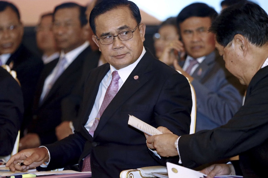 Prime Minister Prayut Chan-o-cha wears a suit while looking out of the corner of his eye to the left.