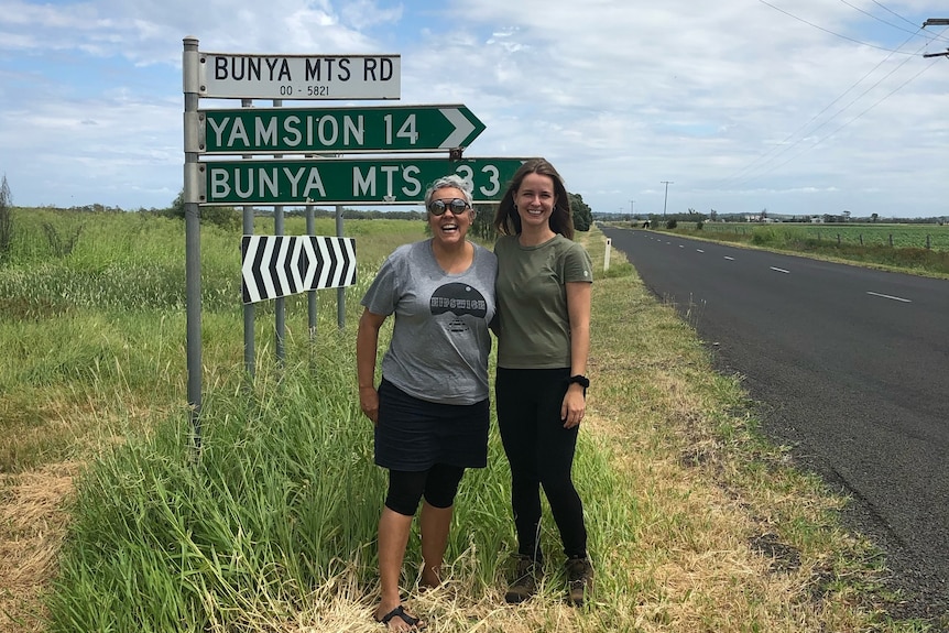 Two women standing next to a sign pointing to the Bunya Mountains.