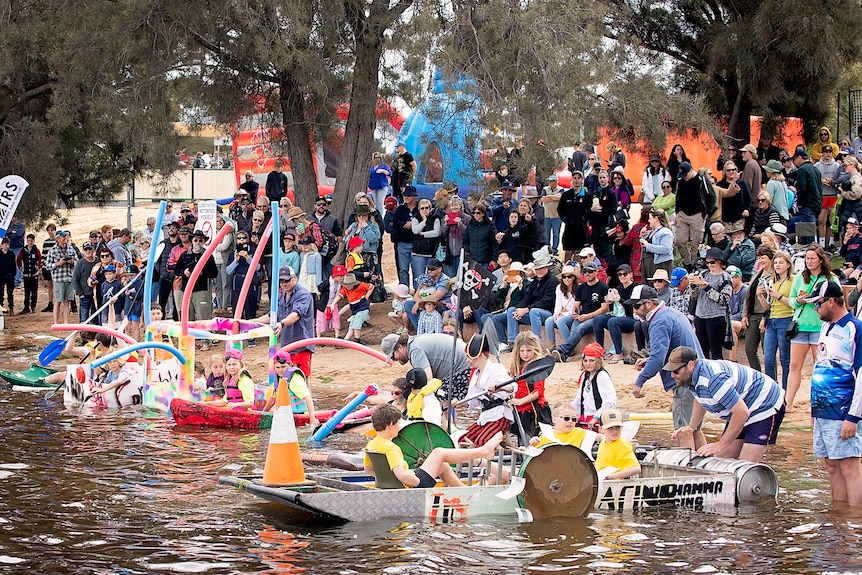A crowd gathered by a lake in fancy dress