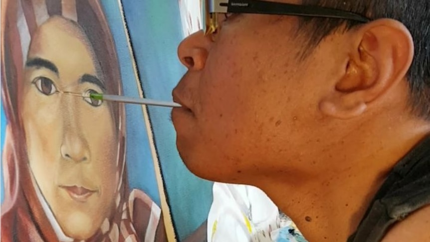 Disabled Indonesian artist Faisal Rusdi paints with his mouth (Photo: Cucu Saidah)