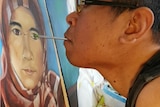 A man painting a portrait of a woman using his mouth