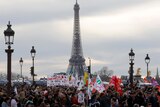 a huge group of protesters march in front of the EIffel tower